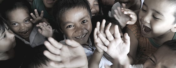 Smiling Philippino school children looking up to camera and waving