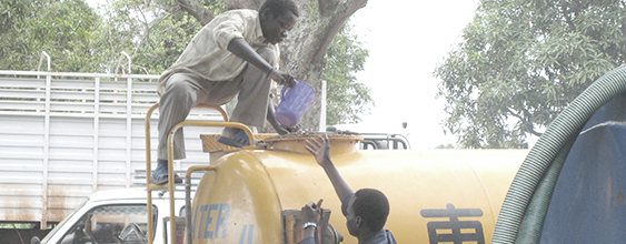Two men supply fresh water from a tanker truck in South Sudan, where WSP implemented a clean water program